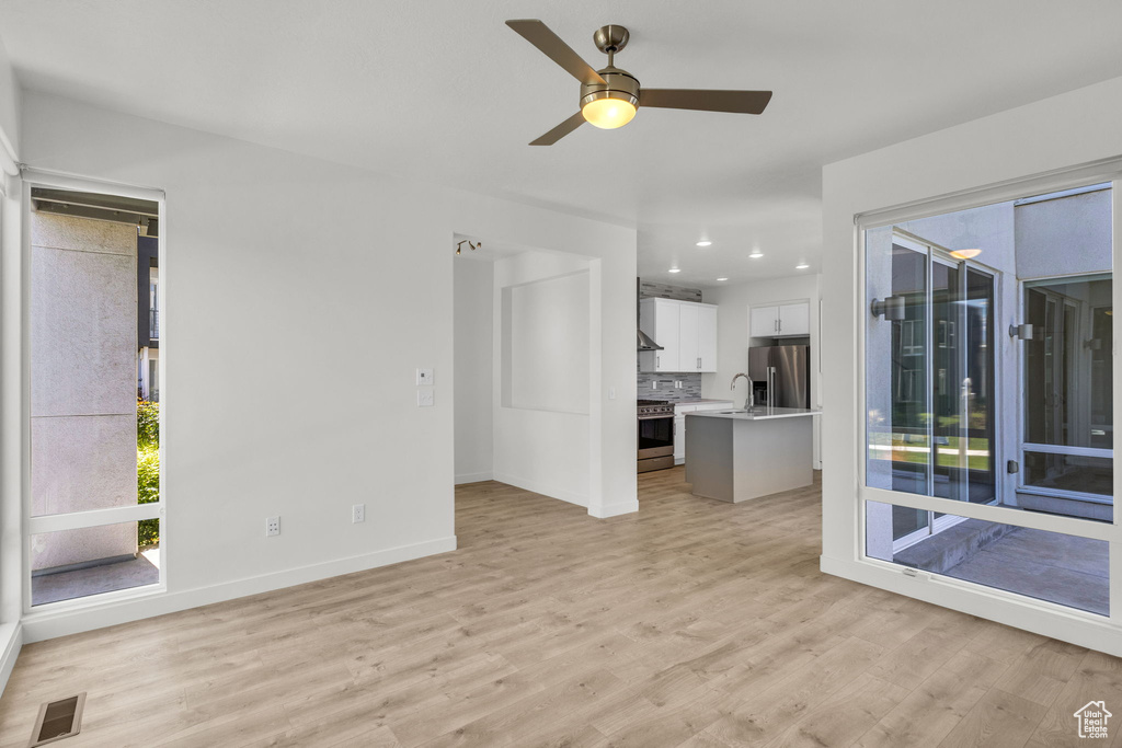 Unfurnished living room featuring light wood finished floors, a ceiling fan, baseboards, and recessed lighting