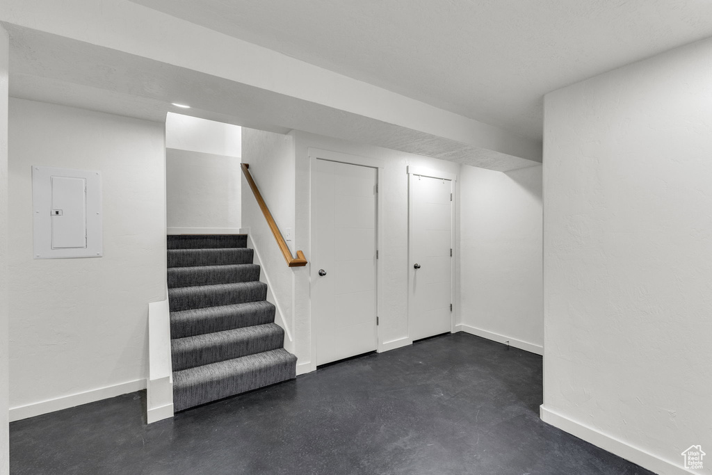 Finished below grade area featuring electric panel, stairway, and baseboards