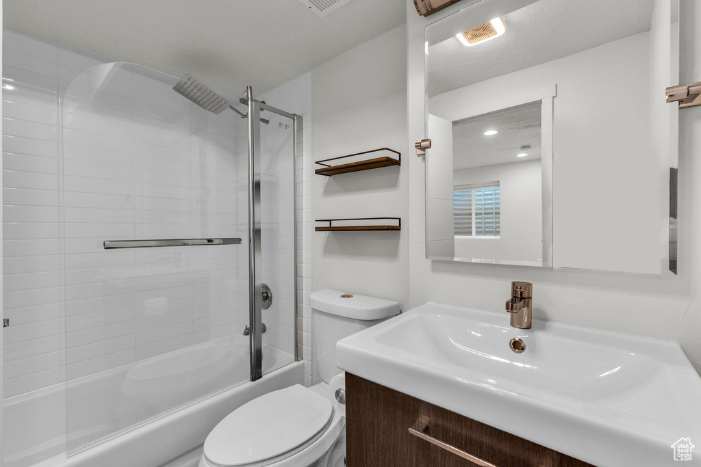 Full bath featuring toilet, vanity, and enclosed tub / shower combo