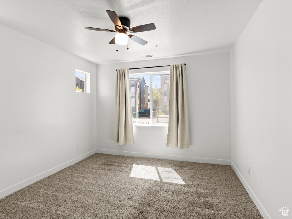 Empty room with ceiling fan, baseboards, carpet flooring, and visible vents