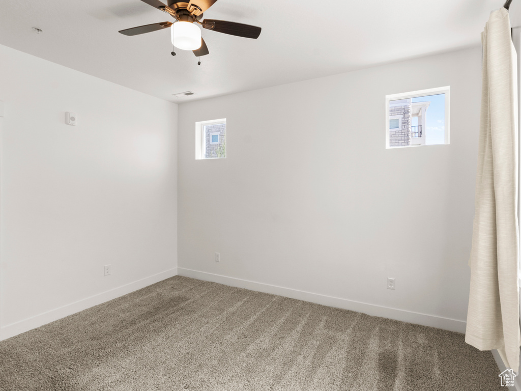 Spare room featuring visible vents, carpet floors, ceiling fan, and baseboards