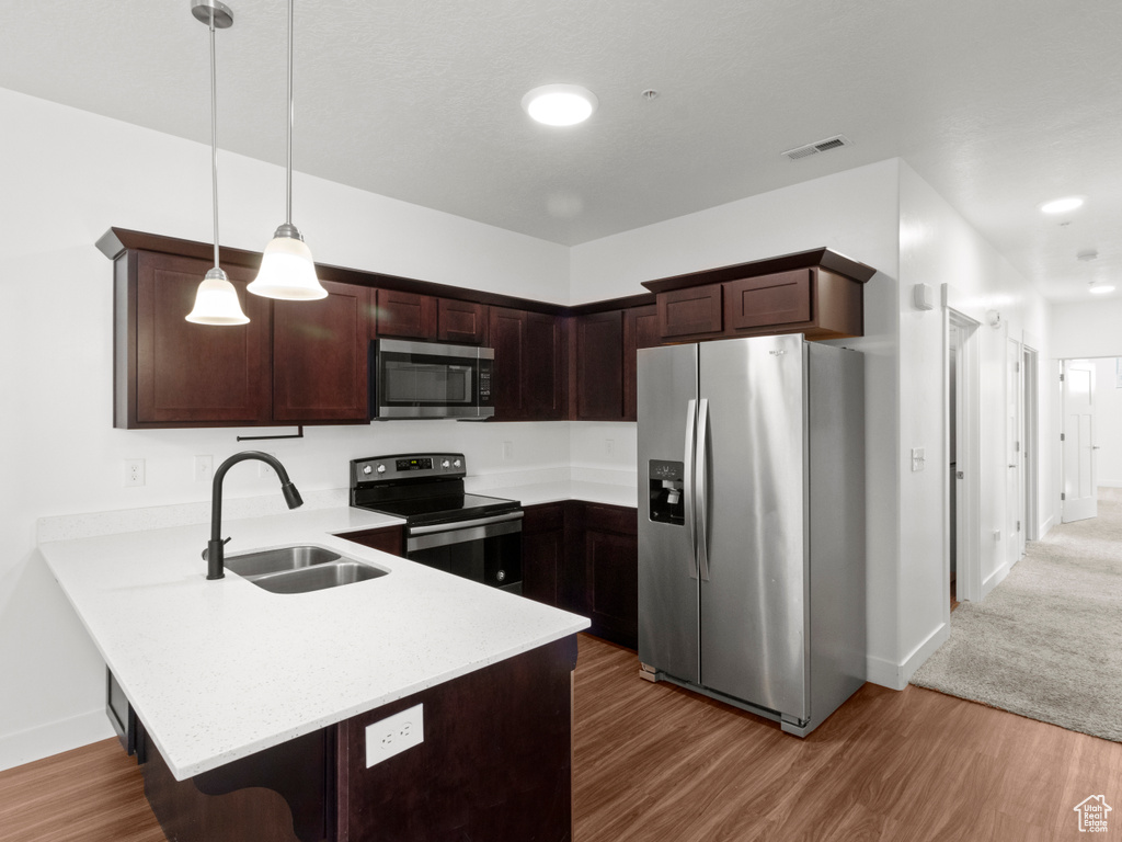 Kitchen with a peninsula, light countertops, visible vents, appliances with stainless steel finishes, and a sink