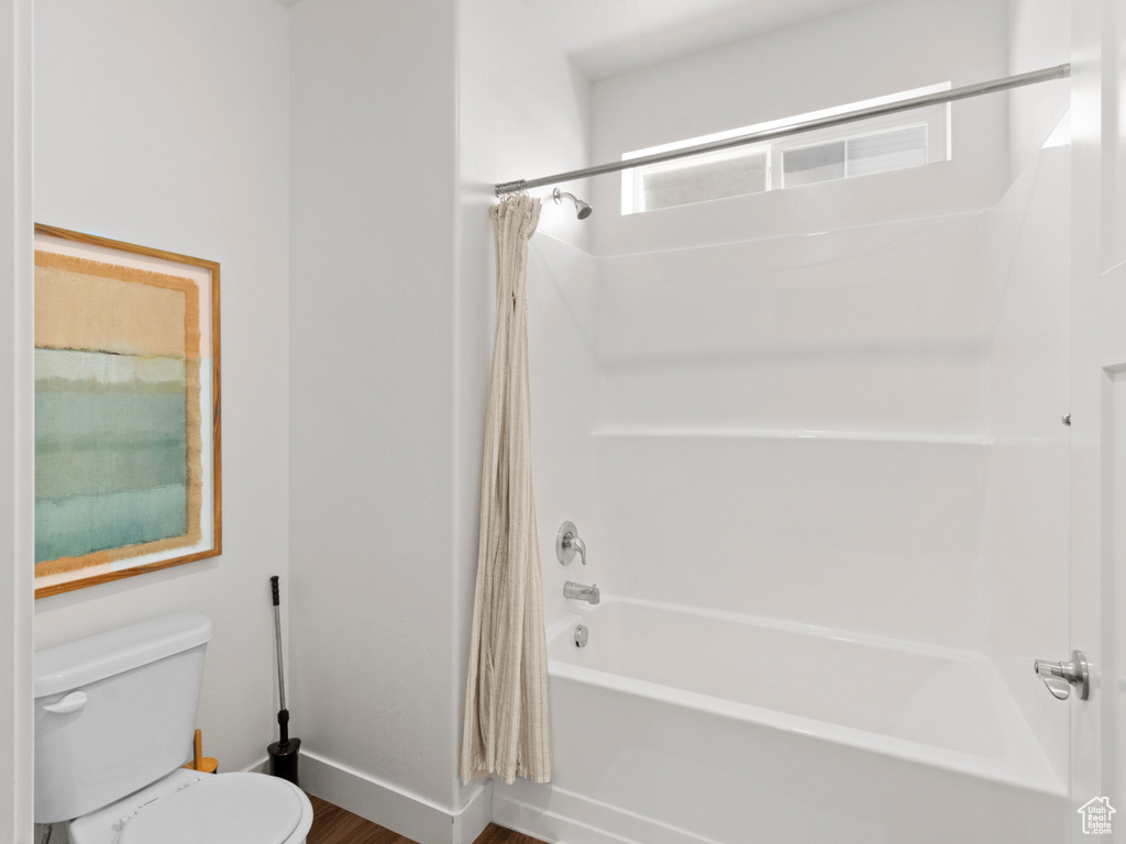 Bathroom with shower / bath combo, baseboards, toilet, and wood finished floors