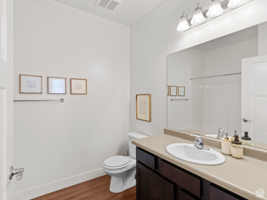 Full bathroom featuring vanity, baseboards, toilet, visible vents, and wood finished floors