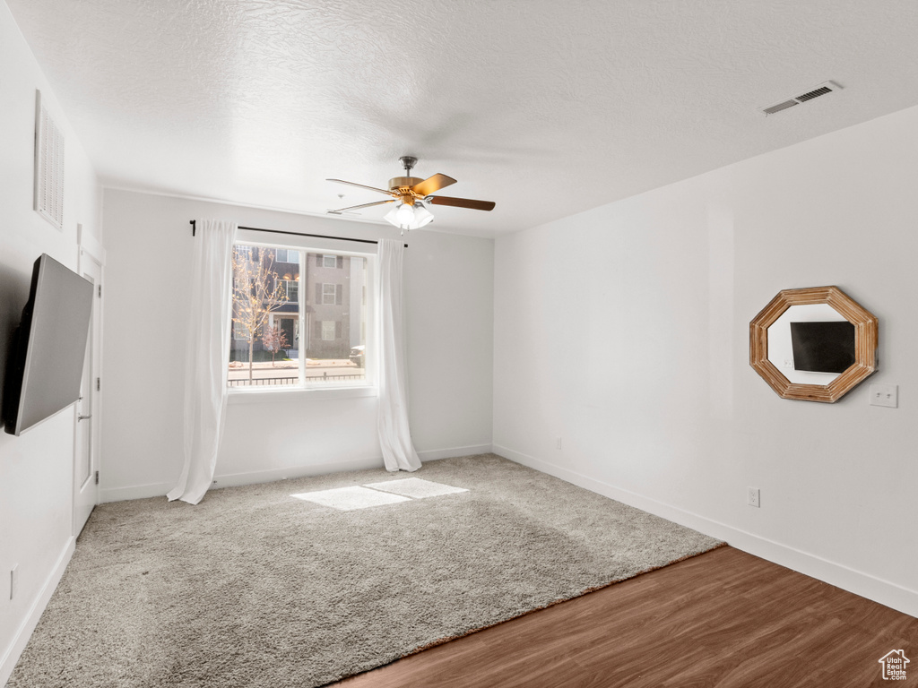 Unfurnished living room with visible vents, baseboards, a ceiling fan, a textured ceiling, and wood finished floors