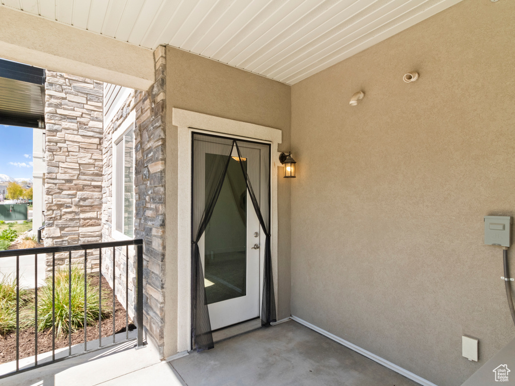 Property entrance with a balcony, stucco siding, and stone siding