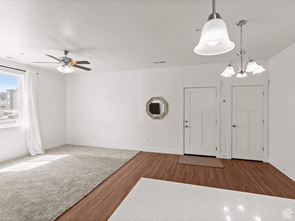 Entryway featuring wood finished floors, ceiling fan with notable chandelier, baseboards, and visible vents
