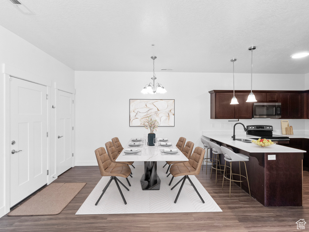 Dining area with dark wood-type flooring, visible vents, baseboards, and an inviting chandelier