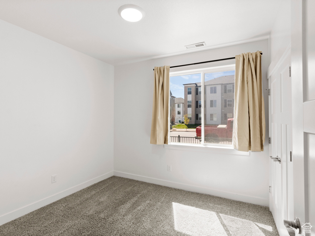 Unfurnished room featuring visible vents, baseboards, and carpet