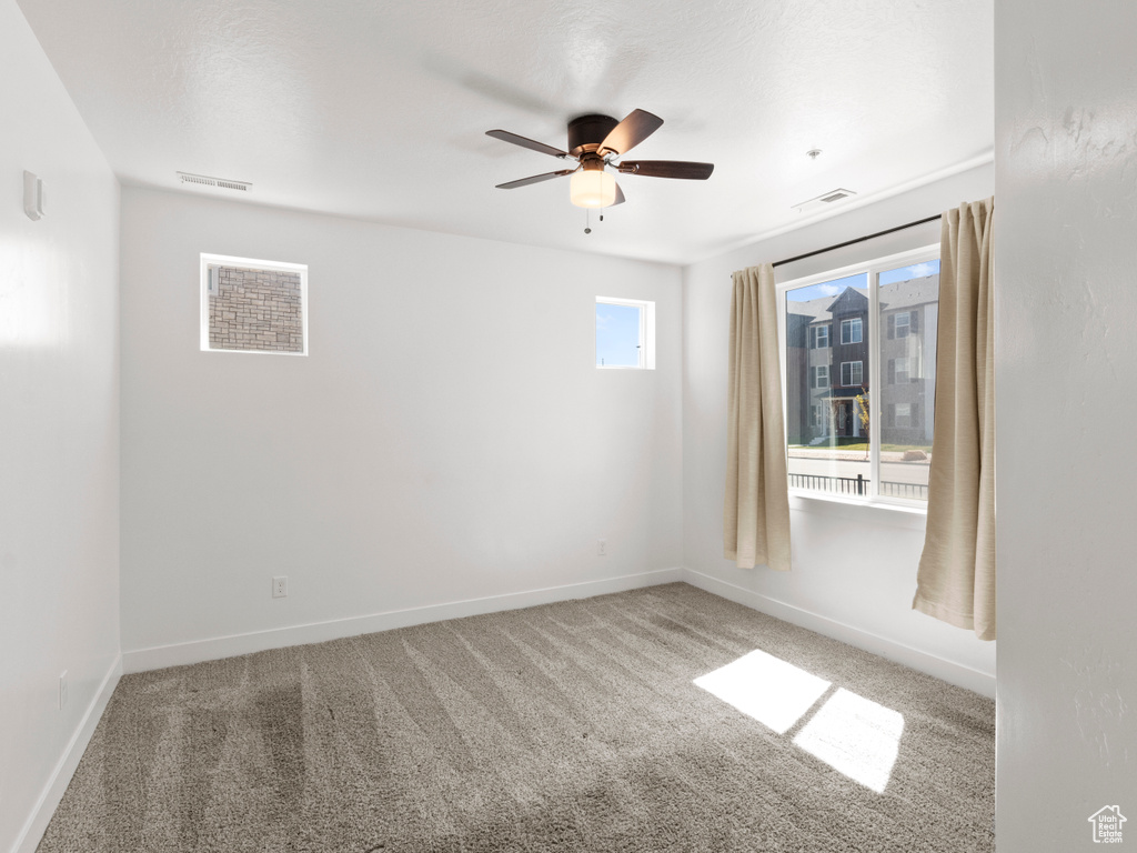 Empty room featuring visible vents, baseboards, a ceiling fan, and carpet floors