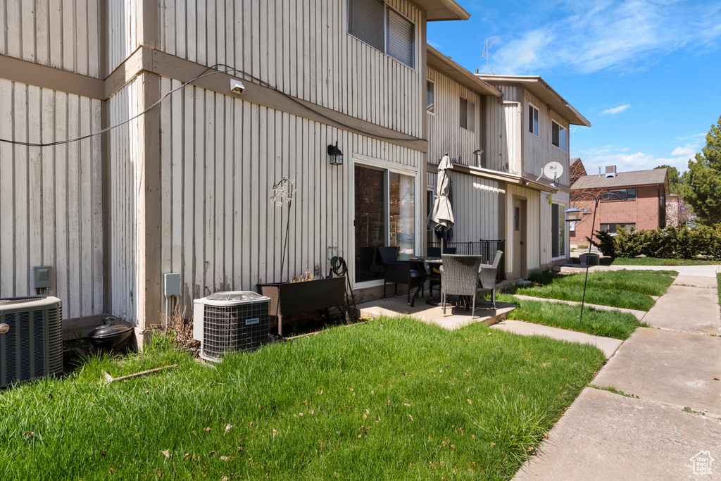 Rear view of house with a yard, central AC unit, and a patio area