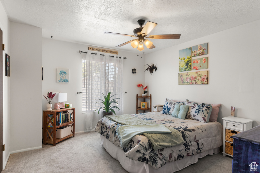 Bedroom with light carpet, a textured ceiling, baseboards, and ceiling fan