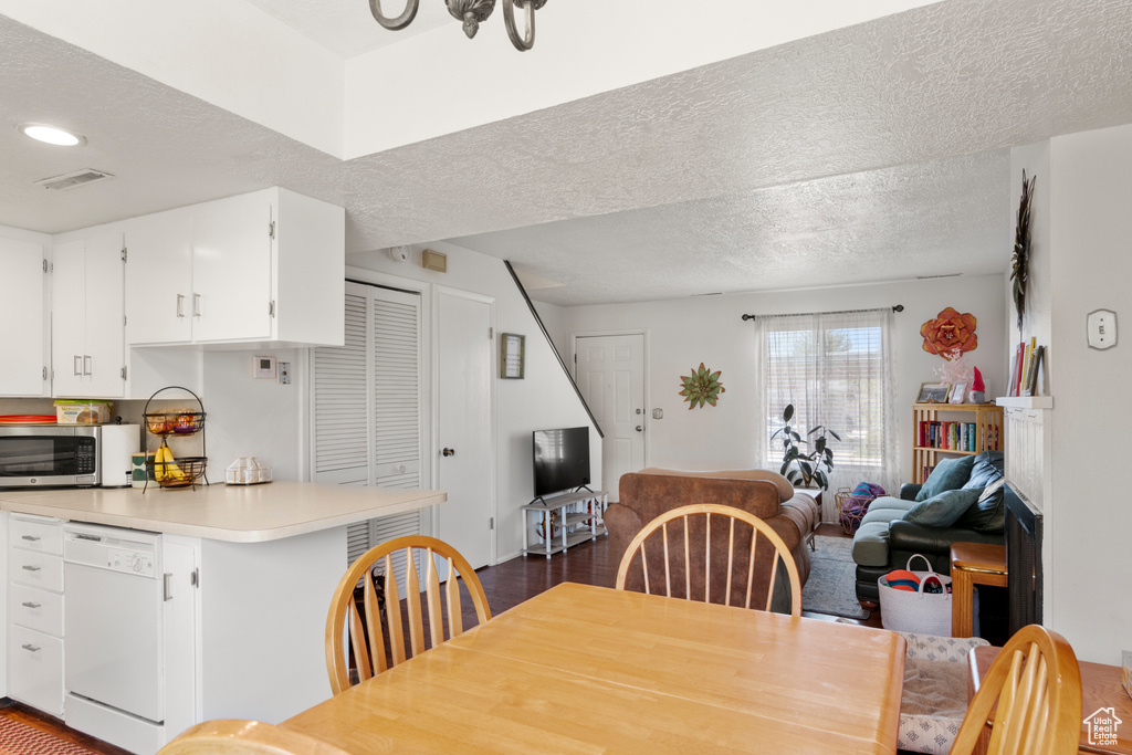 Dining room featuring visible vents, a textured ceiling, and dark wood finished floors