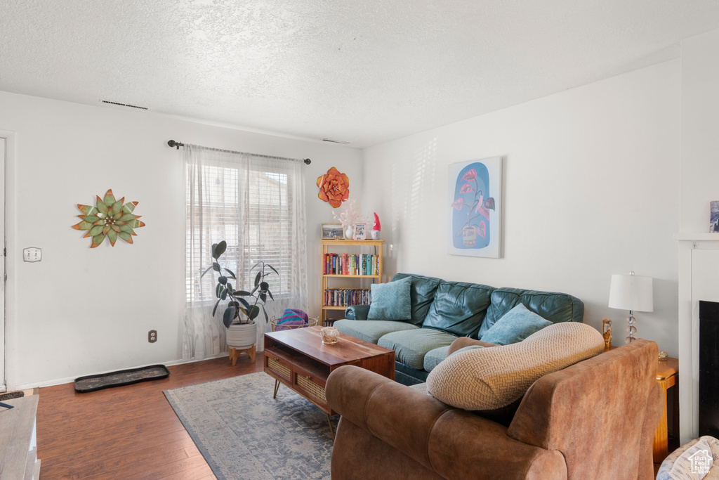 Living area featuring baseboards, wood finished floors, and a textured ceiling