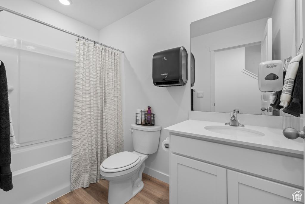 Full bath with shower / tub combo, vanity, toilet, and wood finished floors