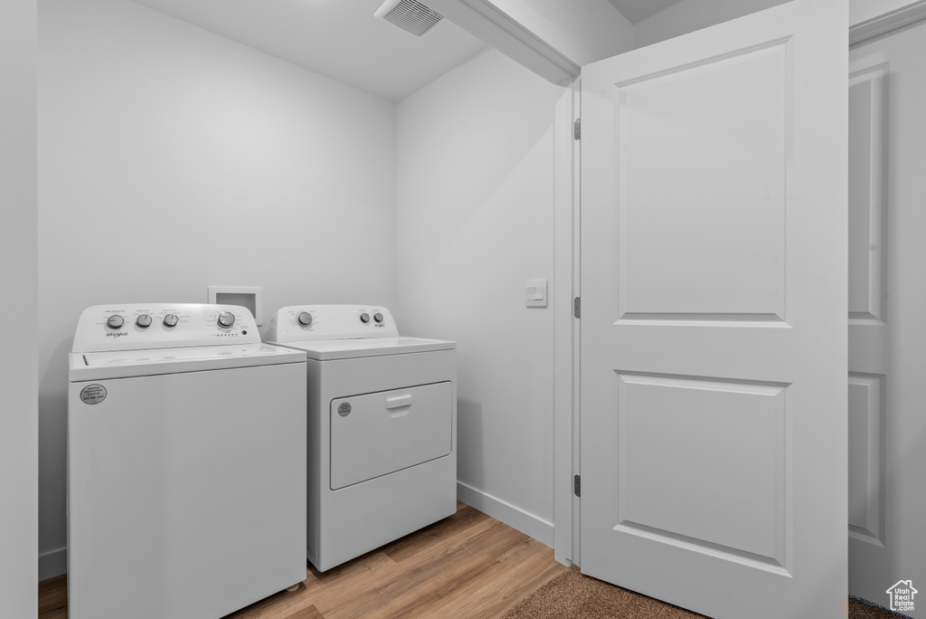 Clothes washing area with visible vents, baseboards, light wood-style floors, laundry area, and independent washer and dryer