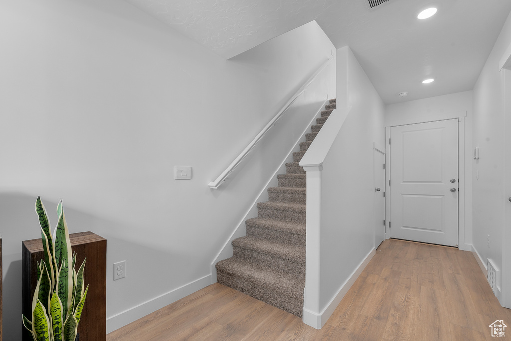 Stairway featuring visible vents, baseboards, recessed lighting, and wood finished floors