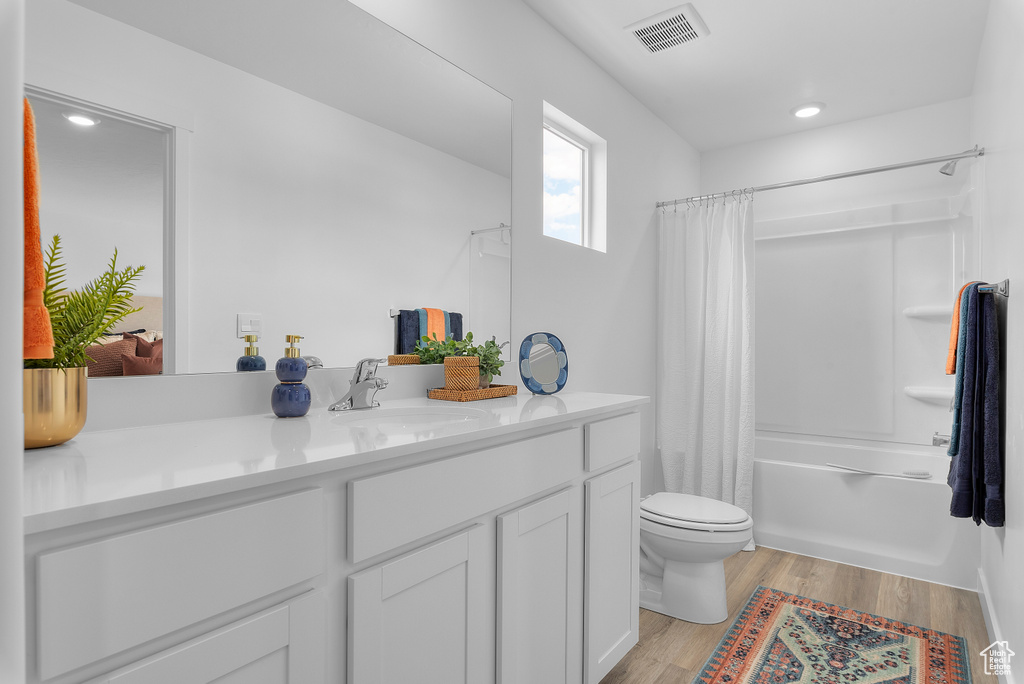 Full bathroom featuring shower / tub combo, vanity, toilet, visible vents, and wood finished floors