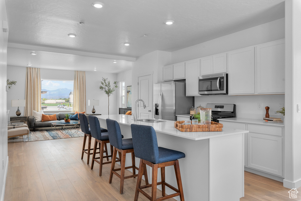 Kitchen with a sink, a kitchen island with sink, a kitchen bar, and stainless steel appliances