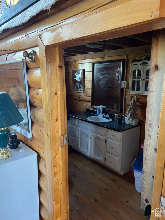Bathroom with rustic walls, vanity, and wood-type flooring