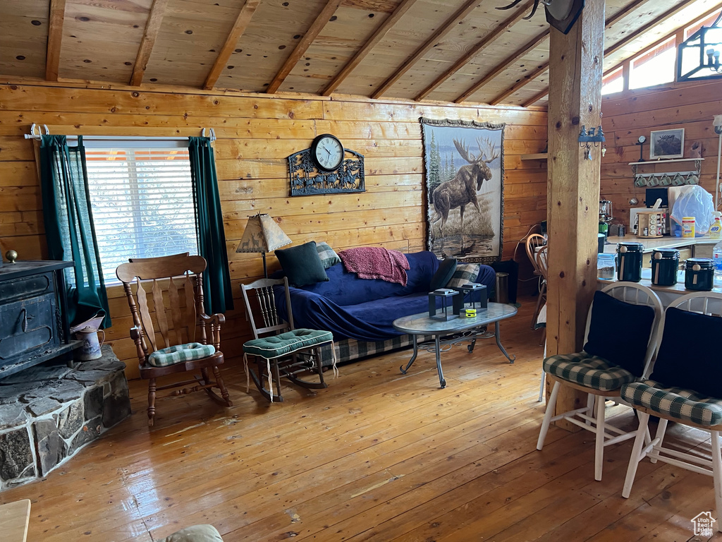 Living area featuring hardwood / wood-style floors, wood walls, and vaulted ceiling with beams