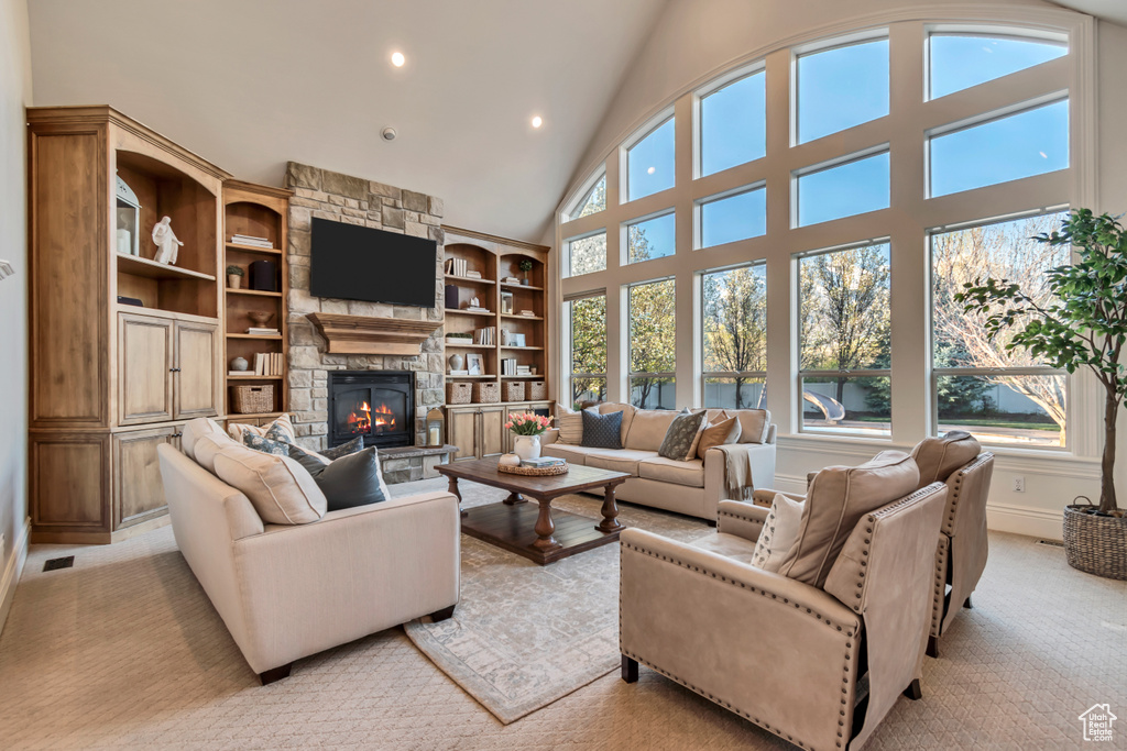Living room featuring baseboards, a stone fireplace, recessed lighting, high vaulted ceiling, and light colored carpet