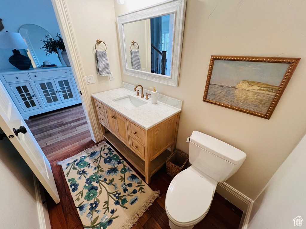 Bathroom with toilet, vanity, and wood finished floors