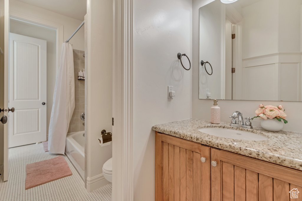 Full bathroom featuring toilet, shower / bathtub combination with curtain, vanity, and tile patterned flooring
