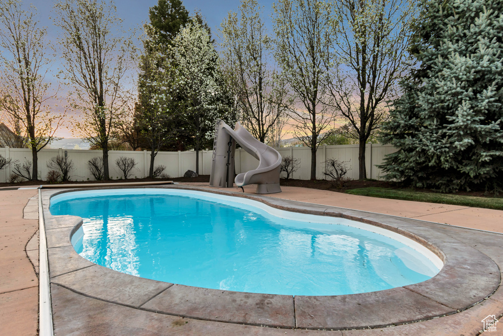 View of pool with a fenced in pool, a patio area, a fenced backyard, and a water slide