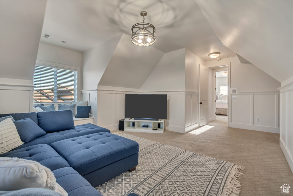 Living room featuring light carpet, a decorative wall, plenty of natural light, and lofted ceiling