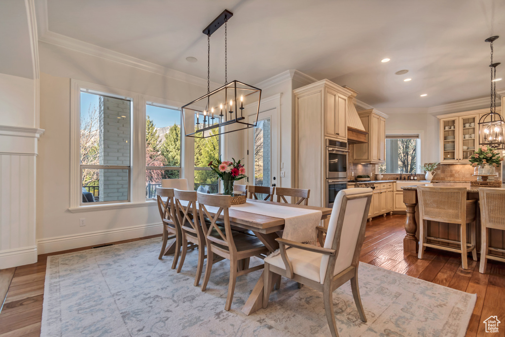 Dining room with baseboards, a chandelier, recessed lighting, crown molding, and hardwood / wood-style floors