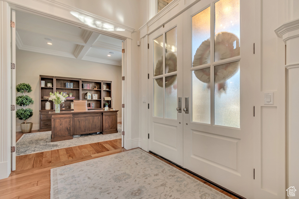 Foyer entrance featuring beamed ceiling, light wood-type flooring, ornamental molding, coffered ceiling, and french doors