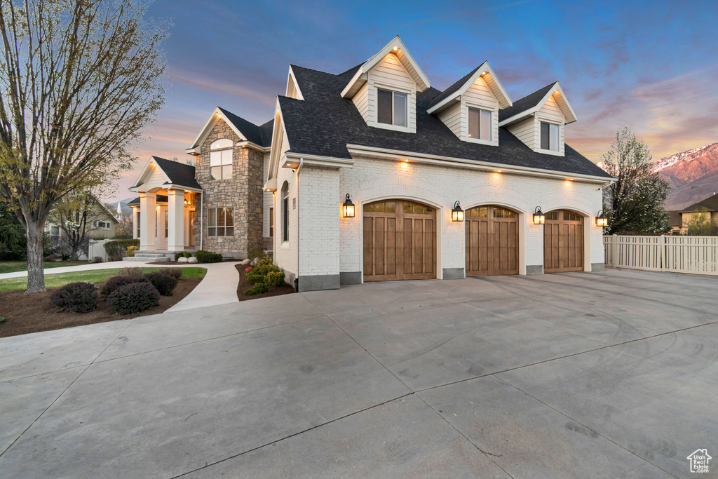 View of front of property with brick siding, an attached garage, fence, and driveway