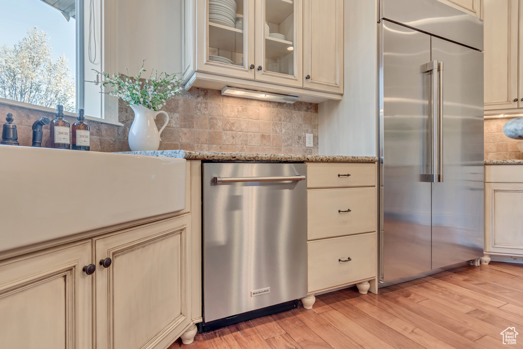 Kitchen with light wood-type flooring, cream cabinets, and stainless steel appliances