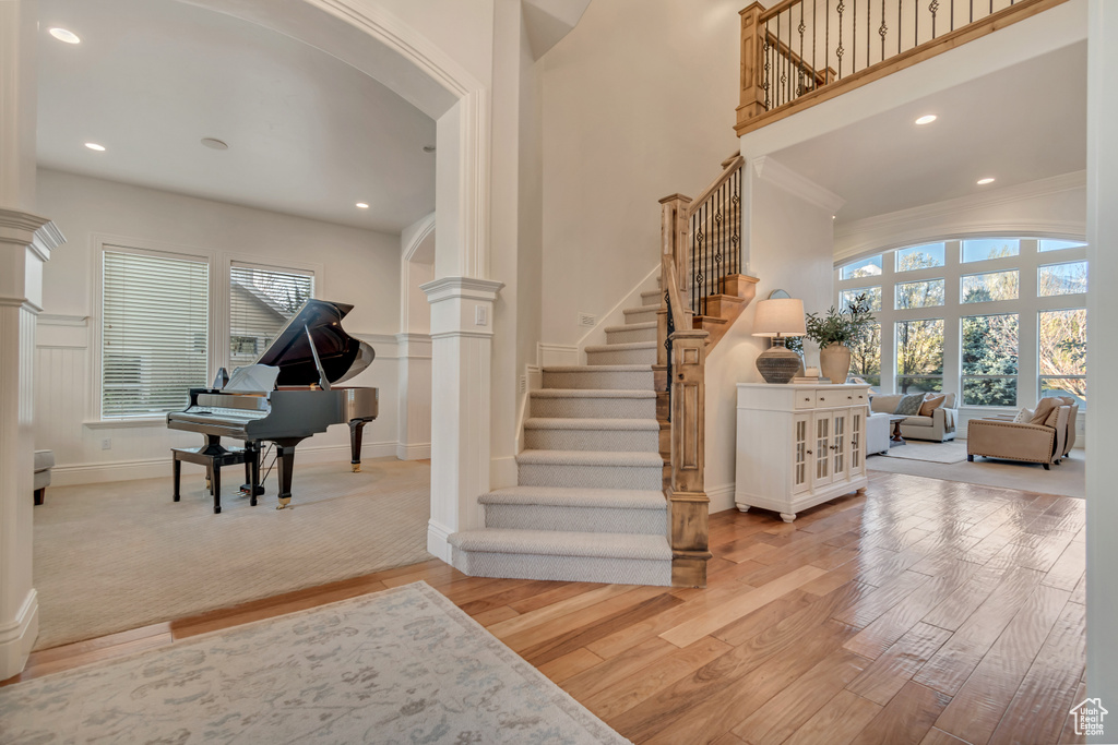 Foyer with ornate columns, plenty of natural light, wood finished floors, and stairway