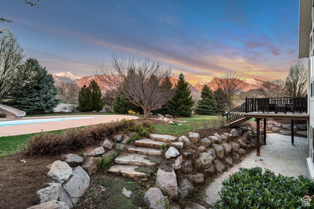 Yard at dusk featuring an outdoor pool, a deck with mountain view, and stairway