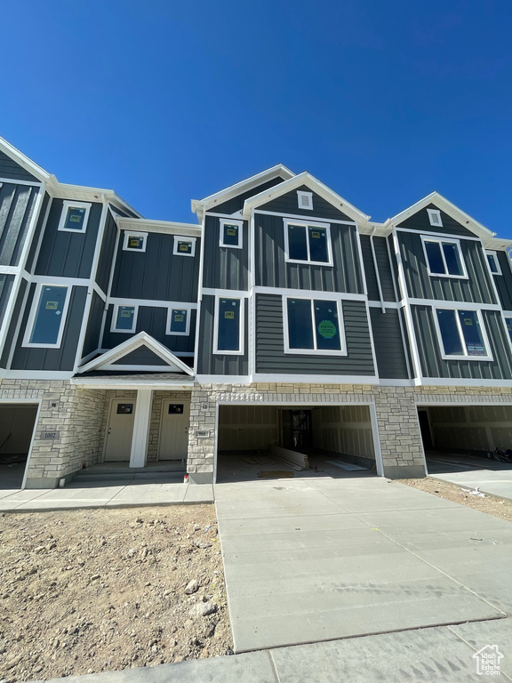 Multi unit property with an attached garage, concrete driveway, stone siding, and board and batten siding