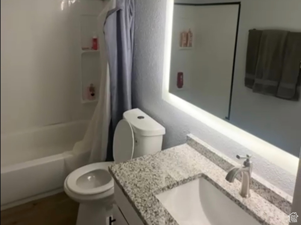 Full bath with shower / bathtub combination with curtain, vanity, visible vents, toilet, and wood finished floors