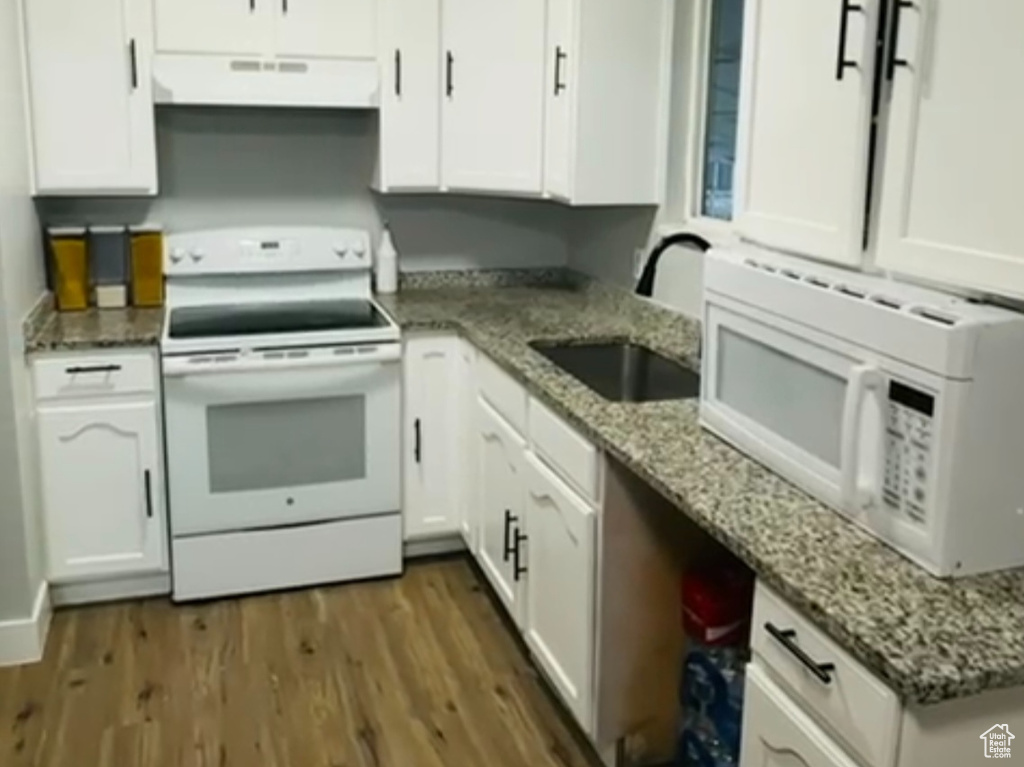 Kitchen featuring a sink, white cabinetry, white appliances, and under cabinet range hood