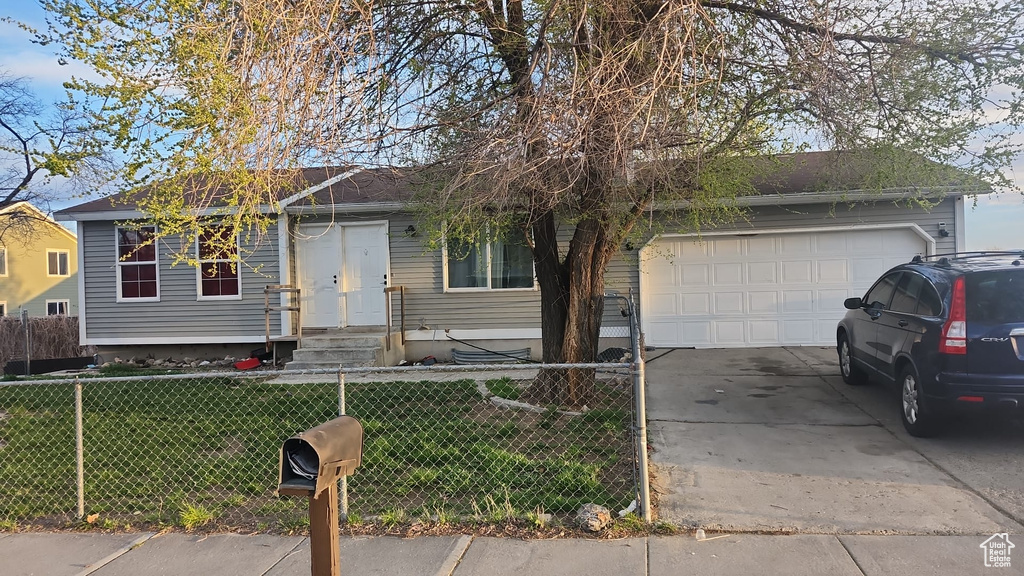 Single story home featuring a fenced front yard, a front lawn, an attached garage, and concrete driveway