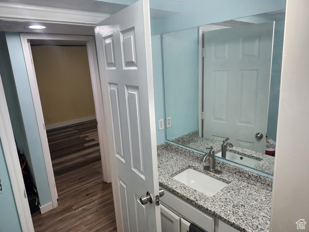 Bathroom featuring wood finished floors, vanity, baseboards, and recessed lighting