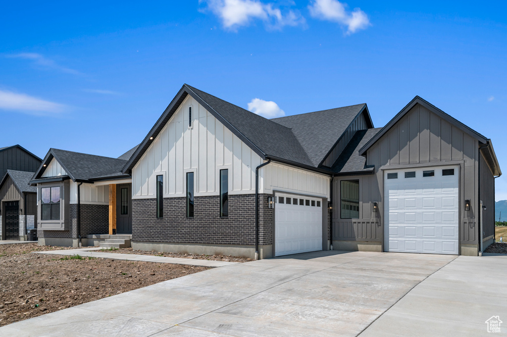 Modern farmhouse style home featuring board and batten siding, a garage, concrete driveway, and a shingled roof
