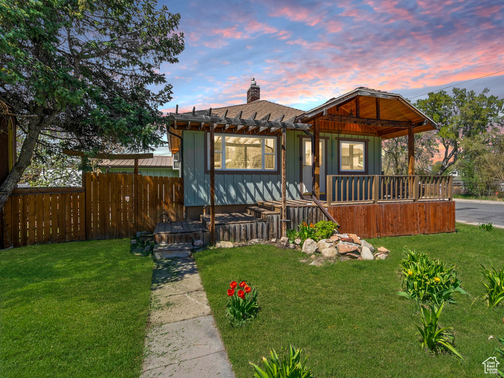View of front of home featuring a chimney, a pergola, board and batten siding, a front lawn, and fence