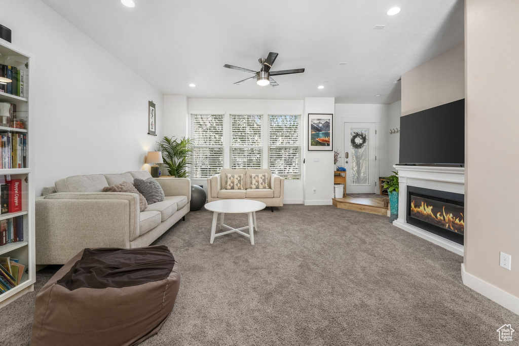 Carpeted living room with a glass covered fireplace, recessed lighting, baseboards, and a ceiling fan