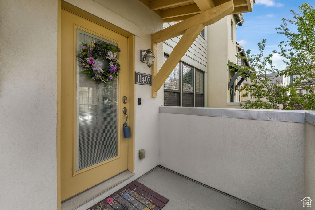 View of exterior entry with a balcony and stucco siding