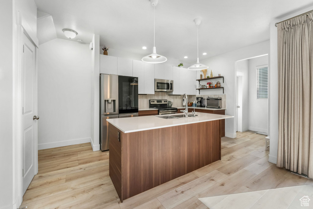 Kitchen featuring open shelves, a sink, light countertops, appliances with stainless steel finishes, and recessed lighting