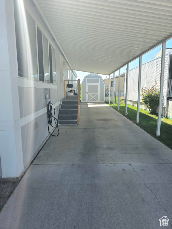 View of patio / terrace featuring a shed, an outdoor structure, an attached carport, and fence