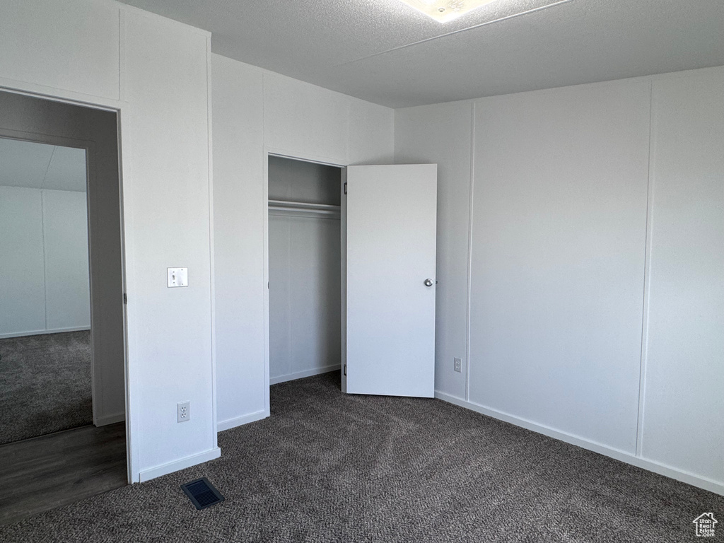 Unfurnished bedroom with dark colored carpet and a closet