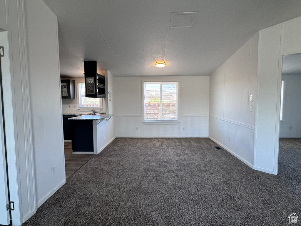 Unfurnished dining area featuring dark carpet and baseboards