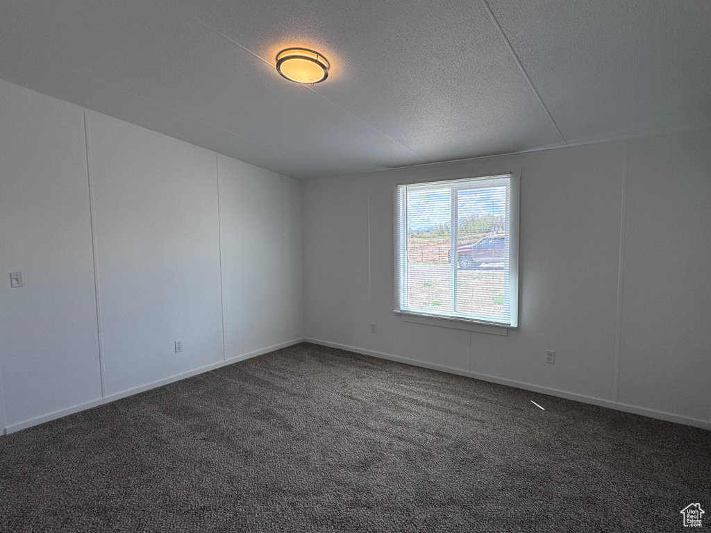 Empty room with carpet, a textured ceiling, and baseboards